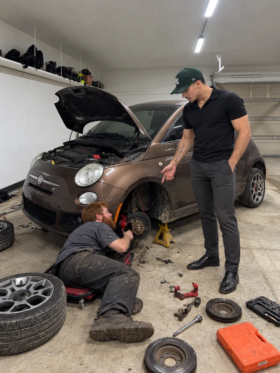 A mechanic working on a car while the rental-car owner observes.